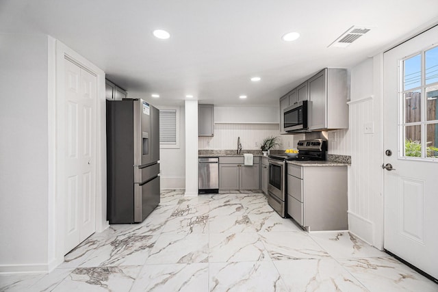 3515 Winnie St, Galveston, TX 77550 - kitchen with appliances with stainless steel finishes, gray cabinetry, recessed lighting, light marble finish flooring, and light stone countertops