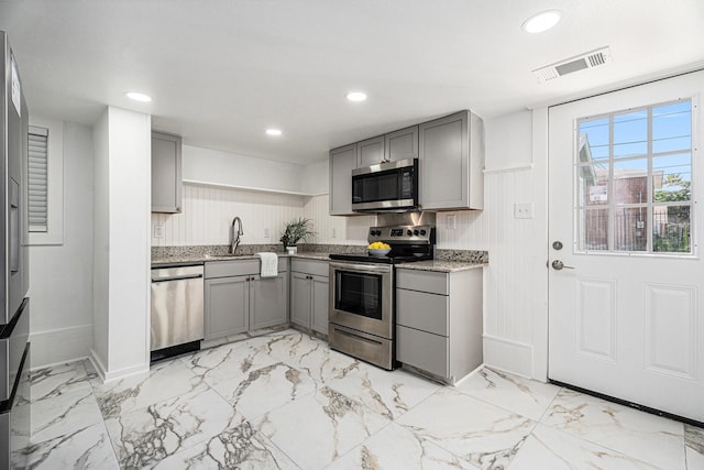 3515 Winnie St, Galveston, TX 77550 - kitchen with stainless steel appliances, gray cabinetry, light stone counters, open shelves, and light marble finish flooring