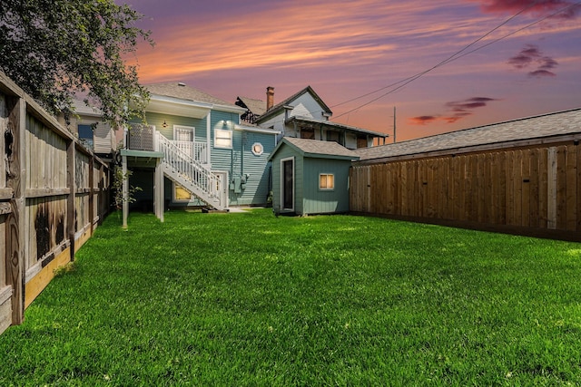 3515 Winnie St, Galveston, TX 77550 - back of property at dusk featuring a storage unit, stairs, a fenced backyard, and roof with shingles