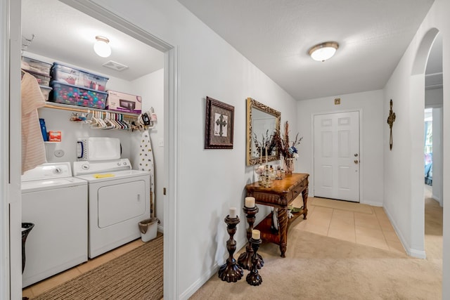 12114 Mabel Ln, Pinehurst, TX 77362 - laundry room featuring washer and dryer, light tile patterned floors, light carpet, and arched walkways