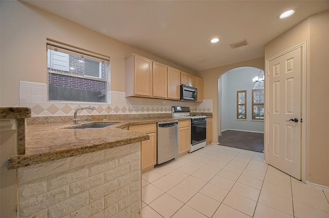 23035 Canal Rd, Richmond, TX 77406 - kitchen featuring white range with gas cooktop, dishwasher, black microwave, arched walkways, and light tile patterned floors