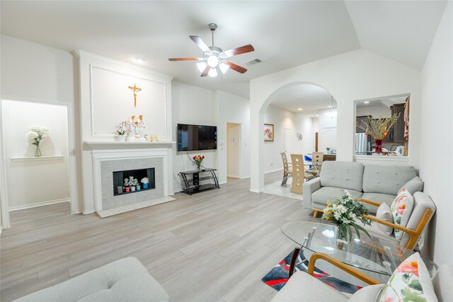 2627 Rosepoint Ct, Fresno, TX 77545 - living room featuring arched walkways, ceiling fan, light wood finished floors, lofted ceiling, and a fireplace with flush hearth