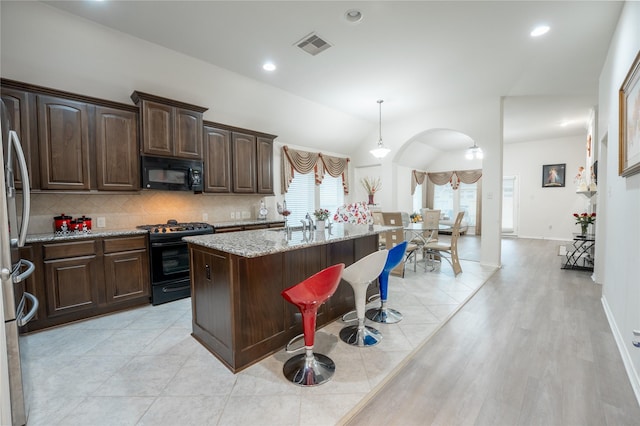 2627 Rosepoint Ct, Fresno, TX 77545 - kitchen featuring black appliances, backsplash, light stone countertops, vaulted ceiling, and arched walkways
