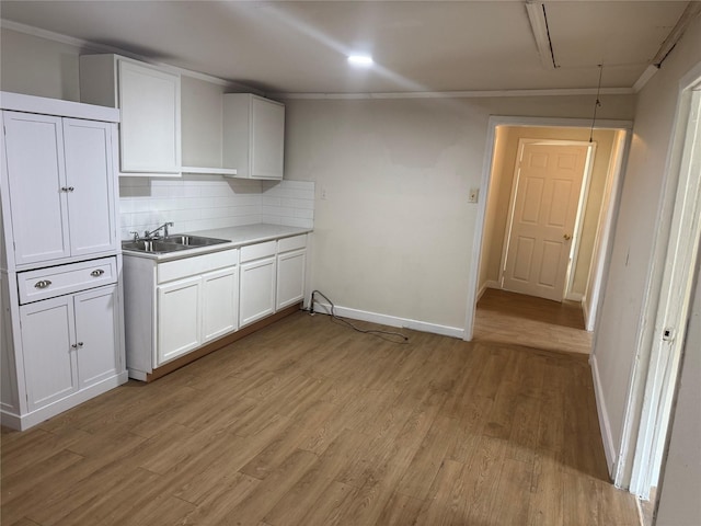 412 Owens St, Houston, TX 77029 - kitchen featuring backsplash, white cabinets, light wood-type flooring, crown molding, and light countertops