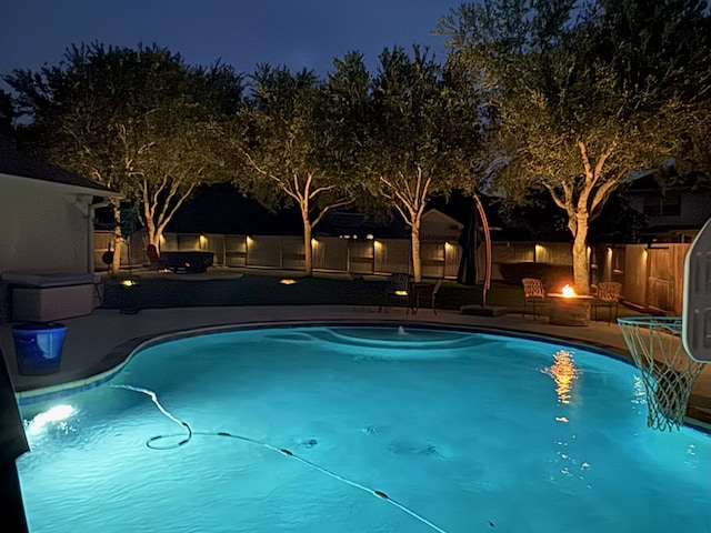 2006 Scarlet Trail Ct, Katy, TX 77494 - pool at night with a patio area, a fenced backyard, and an outdoor fire pit