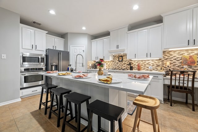 2006 Scarlet Trail Ct, Katy, TX 77494 - kitchen with stainless steel appliances, custom exhaust hood, backsplash, an island with sink, and white cabinetry