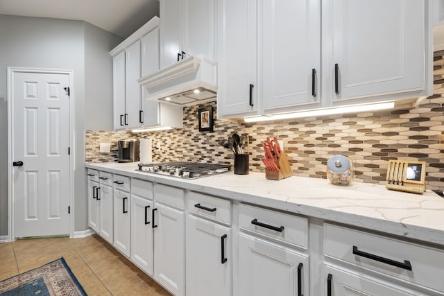 2006 Scarlet Trail Ct, Katy, TX 77494 - kitchen featuring stainless steel gas cooktop, decorative backsplash, white cabinetry, light tile patterned flooring, and light stone countertops
