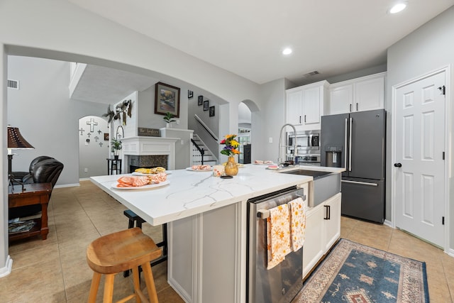 2006 Scarlet Trail Ct, Katy, TX 77494 - kitchen with appliances with stainless steel finishes, arched walkways, light tile patterned floors, a center island with sink, and a fireplace