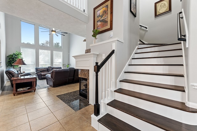 2006 Scarlet Trail Ct, Katy, TX 77494 - stairs with a towering ceiling, a ceiling fan, tile patterned flooring, and a premium fireplace
