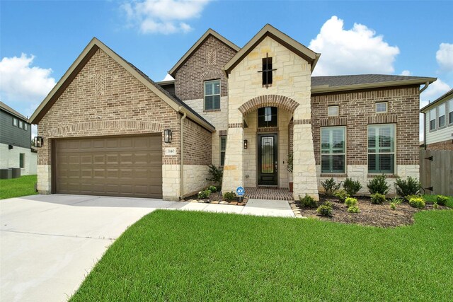 3140 Red Buckeye Ln, Conroe, TX 77301 - french country style house featuring brick siding, concrete driveway, stone siding, and an attached garage