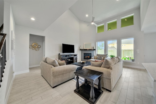 3140 Red Buckeye Ln, Conroe, TX 77301 - living room with a ceiling fan, high vaulted ceiling, light wood-style floors, a glass covered fireplace, and recessed lighting