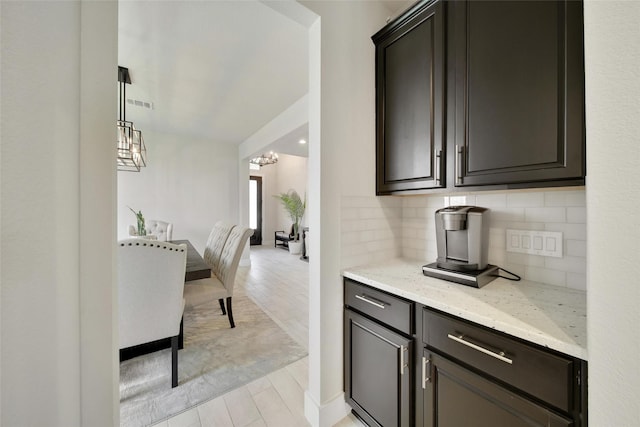 3140 Red Buckeye Ln, Conroe, TX 77301 - bar area featuring decorative backsplash, a chandelier, and light wood-style flooring