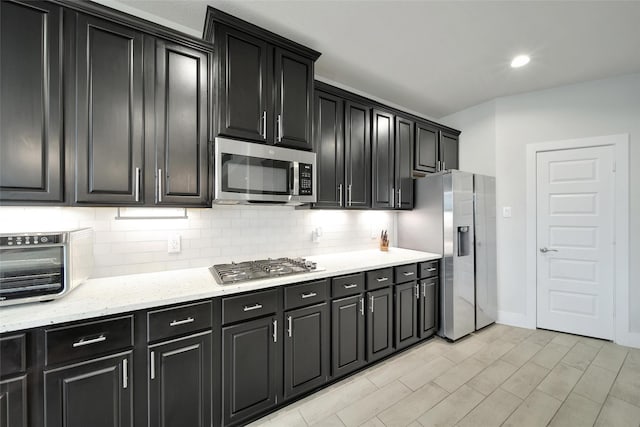 3140 Red Buckeye Ln, Conroe, TX 77301 - kitchen with stainless steel appliances, dark cabinets, tasteful backsplash, light stone countertops, and recessed lighting