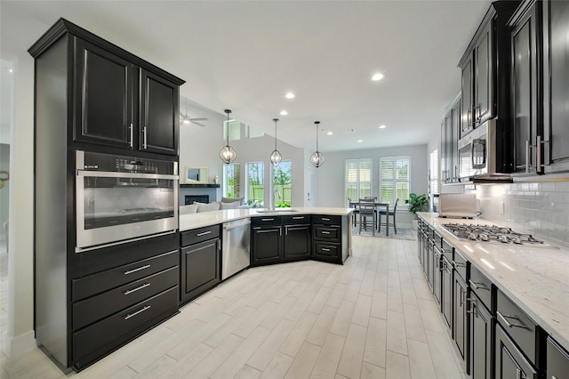 3140 Red Buckeye Ln, Conroe, TX 77301 - kitchen with appliances with stainless steel finishes, dark cabinets, a peninsula, tasteful backsplash, and recessed lighting