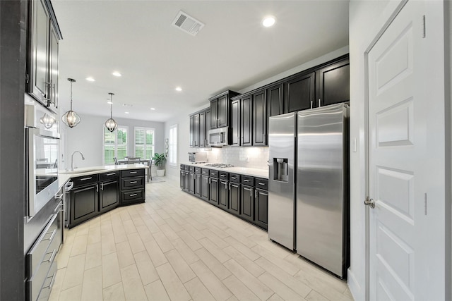 3140 Red Buckeye Ln, Conroe, TX 77301 - kitchen featuring appliances with stainless steel finishes, recessed lighting, dark cabinets, tasteful backsplash, and a peninsula