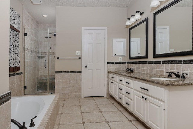 15 Amber Sky Pl, The Woodlands, TX 77381 - bathroom with tile walls, double vanity, a stall shower, a garden tub, and tile patterned floors