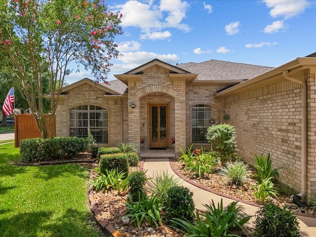 10002 Dawn Brook Dr, Pearland, TX 77584 - property entrance featuring brick siding, roof with shingles, french doors, and a yard
