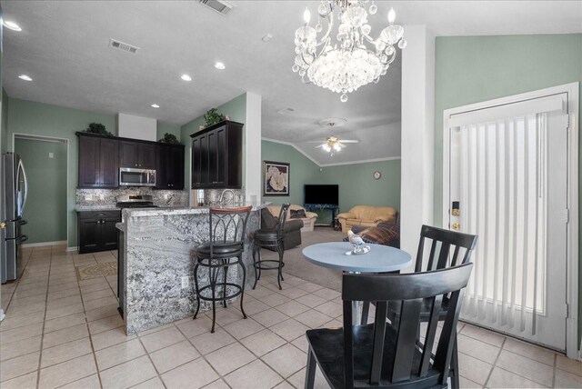 10002 Dawn Brook Dr, Pearland, TX 77584 - kitchen with stainless steel appliances, light tile patterned floors, lofted ceiling, a kitchen bar, and a peninsula