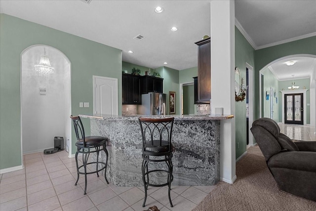 10002 Dawn Brook Dr, Pearland, TX 77584 - kitchen with stainless steel refrigerator with ice dispenser, arched walkways, ornamental molding, a kitchen breakfast bar, and light tile patterned floors