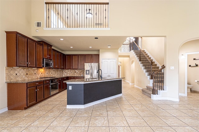 22411 Limestone Crest Ln, Katy, TX 77449 - kitchen with a high ceiling, arched walkways, appliances with stainless steel finishes, backsplash, and a center island with sink