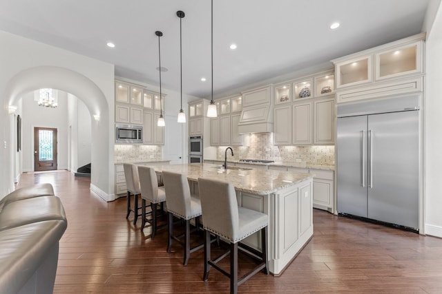 4038 Sabine Valley Trl, Spring, TX 77386 - kitchen featuring built in appliances, a large island, arched walkways, tasteful backsplash, and a breakfast bar