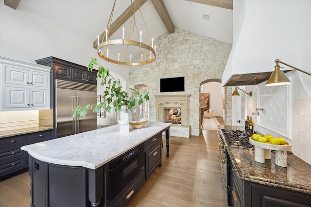10825 Smithdale Rd, Houston, TX 77024 - kitchen with built in appliances, beam ceiling, light stone counters, wood finished floors, and high vaulted ceiling