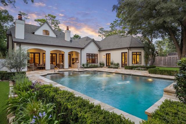 10825 Smithdale Rd, Houston, TX 77024 - back of house at dusk featuring a chimney, stucco siding, a patio area, and outdoor lounge area