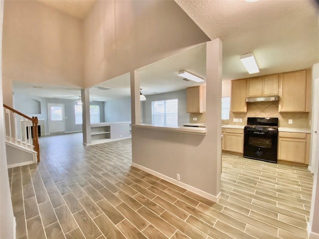 17419 Prospect Meadows Dr, Houston, TX 77095 - kitchen with black gas range oven, light brown cabinetry, under cabinet range hood, light wood finished floors, and a textured ceiling