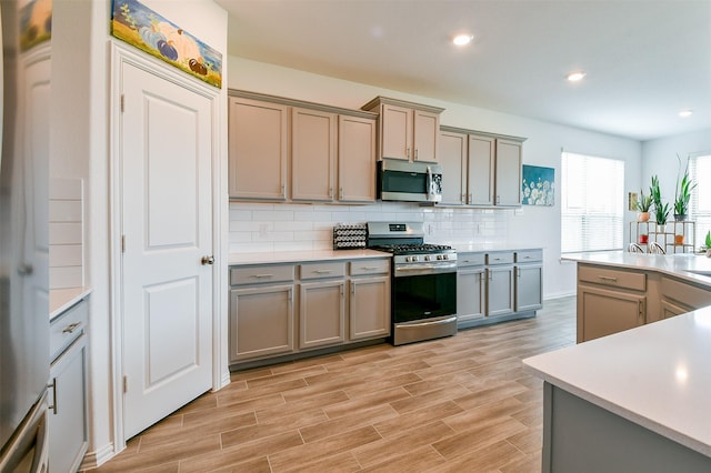 4437 Jessamine Creek Trl, Rosharon, TX 77583 - kitchen with appliances with stainless steel finishes, gray cabinets, decorative backsplash, light countertops, and recessed lighting