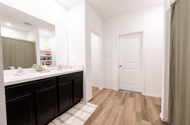 21427 Hawthorn Prairie Dr, New Caney, TX 77357 - bathroom with wood finished floors, double vanity, a shower with shower curtain, and recessed lighting