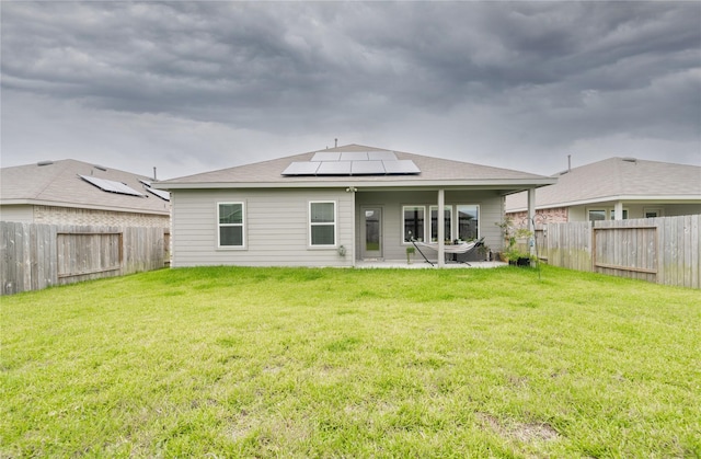 21427 Hawthorn Prairie Dr, New Caney, TX 77357 - back of property with roof mounted solar panels, a patio area, a fenced backyard, and a shingled roof