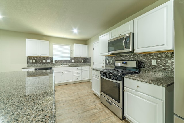 10126 Relic Oaks, San Antonio, TX 78240 - kitchen featuring stainless steel appliances, light wood-type flooring, white cabinets, tasteful backsplash, and dark stone countertops