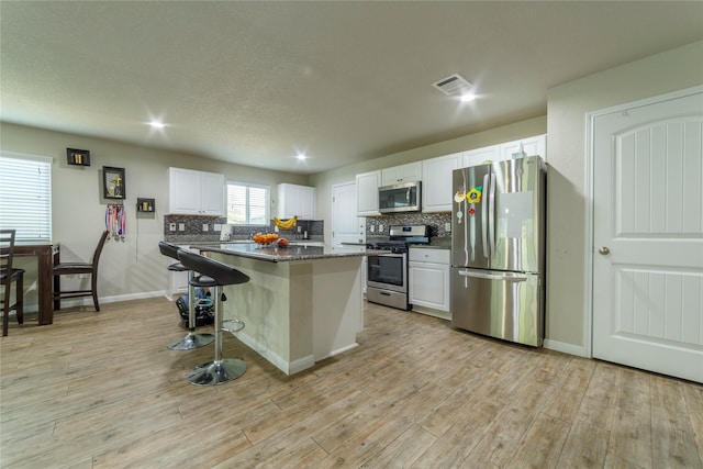 10126 Relic Oaks, San Antonio, TX 78240 - kitchen featuring stainless steel appliances, a kitchen breakfast bar, white cabinets, backsplash, and light wood-style flooring