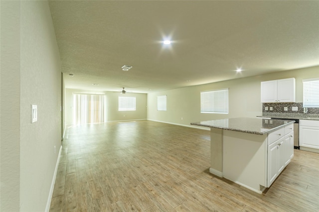 10126 Relic Oaks, San Antonio, TX 78240 - kitchen featuring open floor plan, white cabinets, a kitchen island, decorative backsplash, and light wood-style flooring