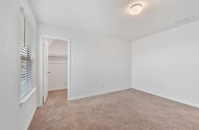 2019 Damasi Ln, Fresno, TX 77545 - unfurnished bedroom featuring carpet, multiple windows, a walk in closet, a closet, and a textured ceiling