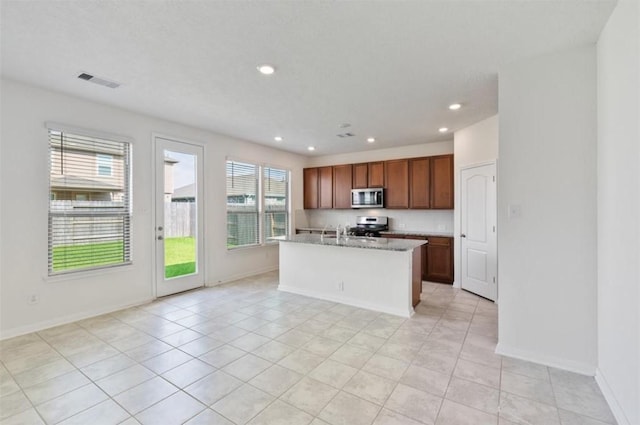2019 Damasi Ln, Fresno, TX 77545 - kitchen featuring appliances with stainless steel finishes, recessed lighting, a center island with sink, light tile patterned floors, and brown cabinets