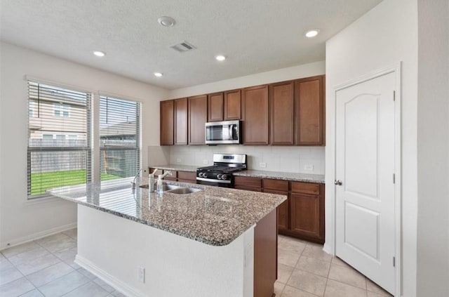 2019 Damasi Ln, Fresno, TX 77545 - kitchen with appliances with stainless steel finishes, a kitchen island with sink, light tile patterned flooring, light stone counters, and recessed lighting