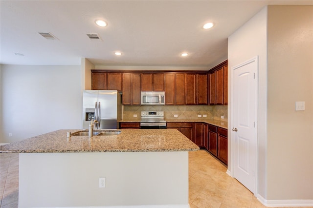8115 Heartbrook Field Ln, Cypress, TX 77433 - kitchen with appliances with stainless steel finishes, light stone countertops, decorative backsplash, an island with sink, and light tile patterned floors