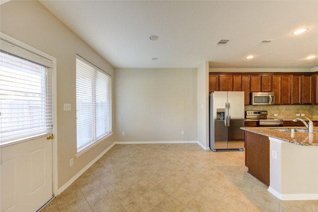 8115 Heartbrook Field Ln, Cypress, TX 77433 - kitchen featuring stainless steel appliances, light stone counters, backsplash, brown cabinets, and recessed lighting