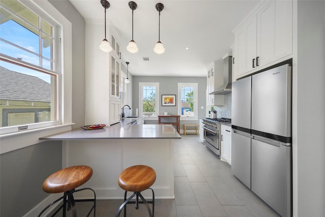 3815 Avenue N 1/2 Ave N 1/2, Galveston, TX 77550 - kitchen with stainless steel appliances, wall chimney exhaust hood, white cabinetry, a peninsula, and glass insert cabinets