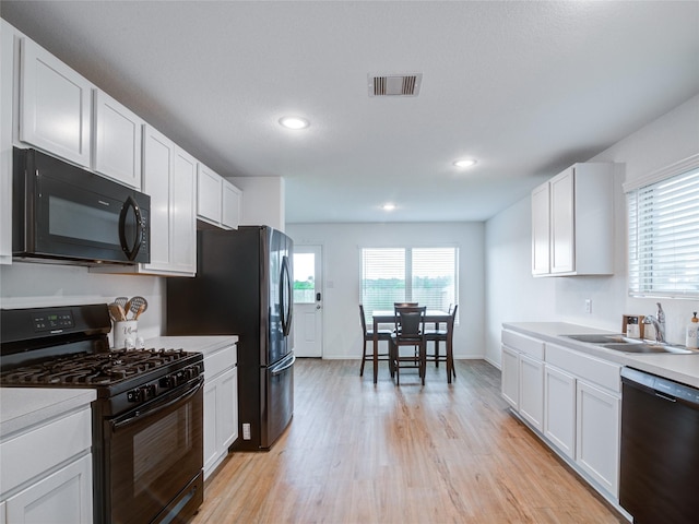 114 Austin Rd, Angleton, TX 77515 - kitchen with black appliances, light wood finished floors, plenty of natural light, white cabinetry, and recessed lighting