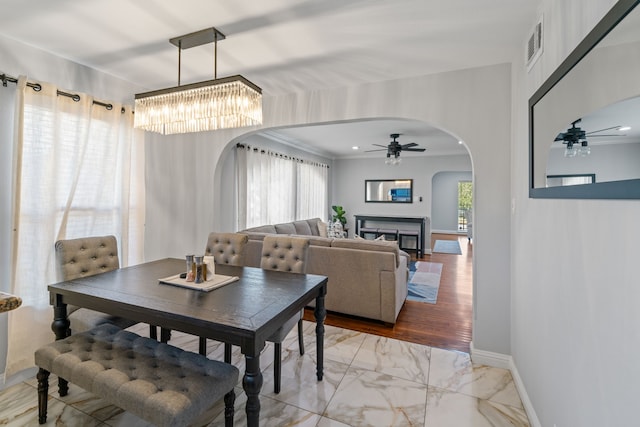 1926 Blodgett St, Houston, TX 77004 - dining room with arched walkways, a ceiling fan, light marble finish flooring, a chandelier, and a glass covered fireplace
