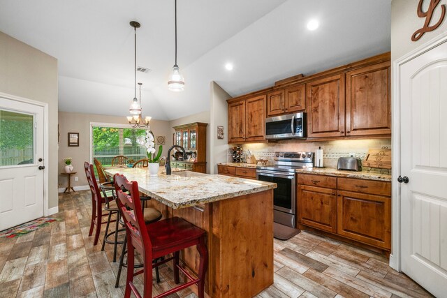 6112 Guyler St, Wallis, TX 77485 - kitchen featuring appliances with stainless steel finishes, brown cabinets, light wood-style floors, vaulted ceiling, and recessed lighting