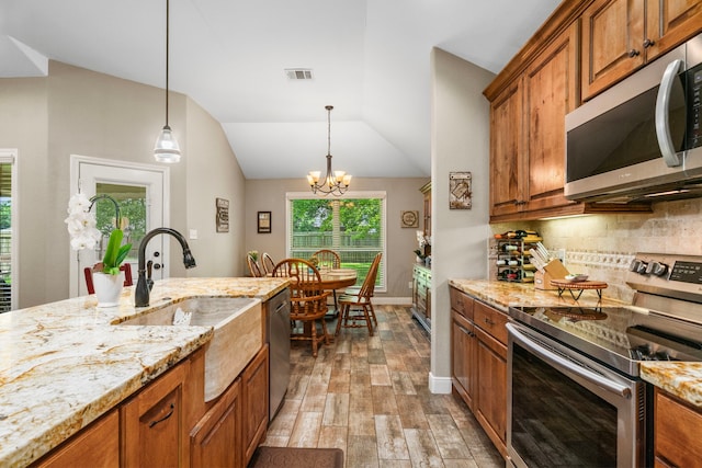 6112 Guyler St, Wallis, TX 77485 - kitchen featuring stainless steel appliances, brown cabinetry, light wood-type flooring, backsplash, and lofted ceiling