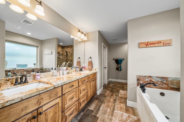 6112 Guyler St, Wallis, TX 77485 - bathroom featuring double vanity, a bath, a tile shower, and wood finished floors