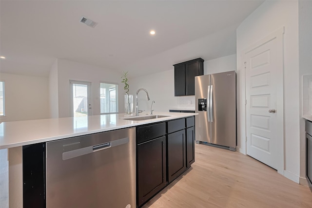30119 Ousel Falls Ln, Katy, TX 77494 - kitchen with stainless steel appliances, a center island with sink, light wood-type flooring, light countertops, and dark cabinets