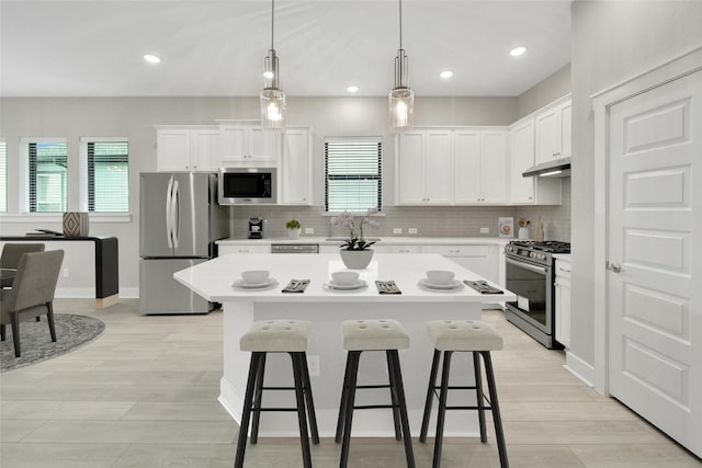 15122 Parkland Canyon Dr, Cypress, TX 77433 - kitchen with stainless steel appliances, under cabinet range hood, a kitchen breakfast bar, light countertops, and recessed lighting