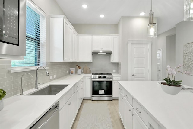 15122 Parkland Canyon Dr, Cypress, TX 77433 - kitchen with stainless steel appliances, under cabinet range hood, white cabinets, light countertops, and backsplash