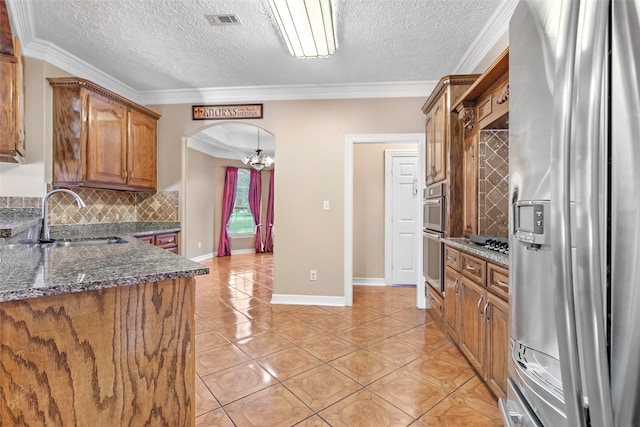 15908 Mcnorton, Splendora, TX 77372 - kitchen featuring stainless steel appliances, brown cabinets, a textured ceiling, tasteful backsplash, and dark stone countertops
