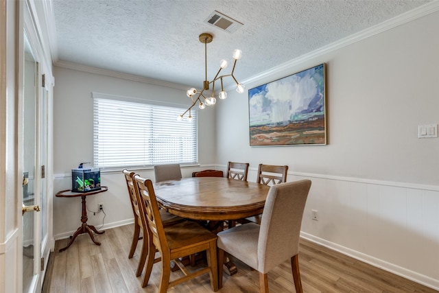 2827 Fontana Dr, Houston, TX 77043 - dining room featuring light wood-style flooring, a textured ceiling, a chandelier, ornamental molding, and a wainscoted wall